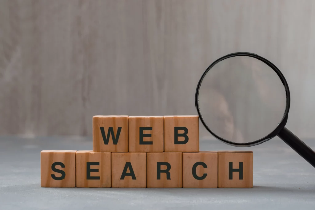 Loupe posée sur des lettre de scrabble, il est écrit "Web search" pour faire référence au fait que les annonces publicitaire sont plus ou moin performante en fonction de la recherche des utilisateurs